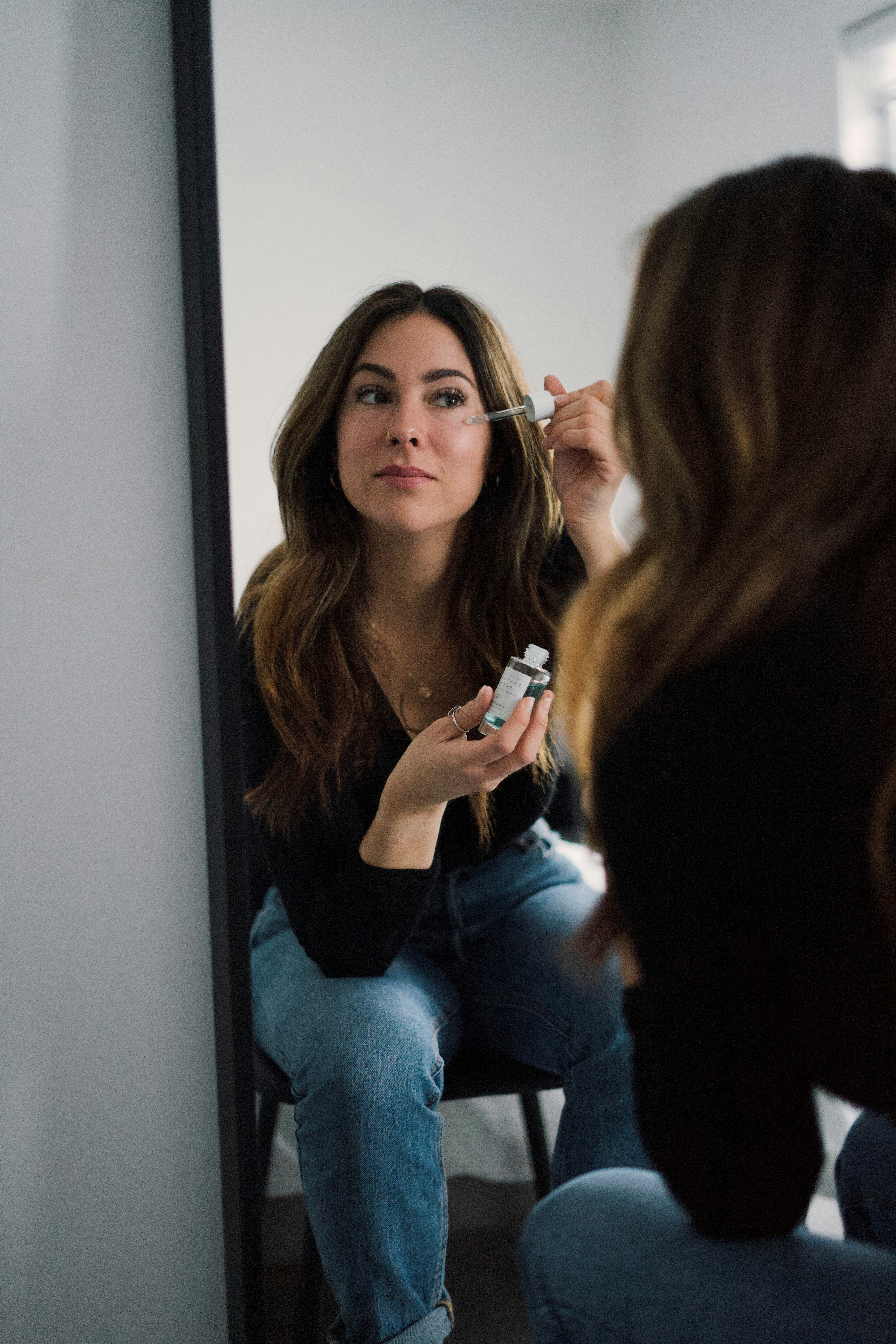 woman in black long sleeve shirt and blue denim jeans sitting on white wooden door